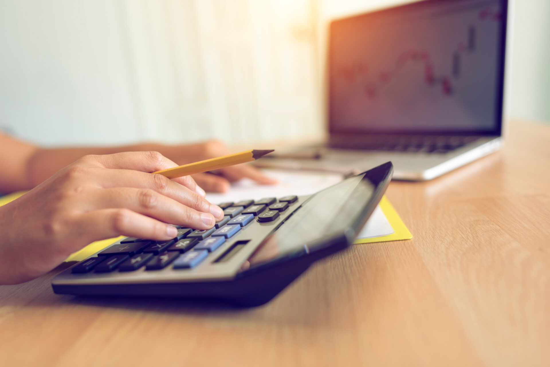 Person using a calculator to estimate invoice factoring costs and financing fees.